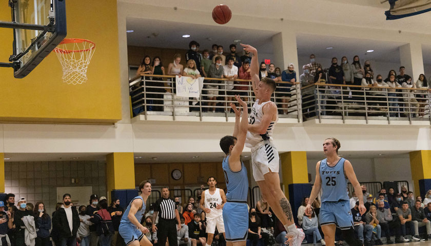 A Suffolk men's basketball player skies for a shot against Tufts University.