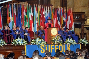 Stage with Suffolk University Deans with flags in the background