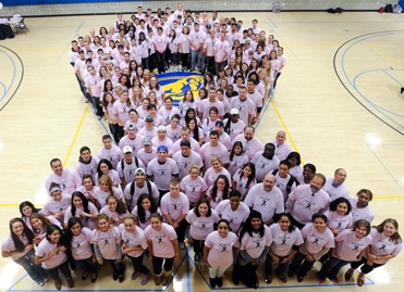 Students and Staff standing in the shape of a ribbon all wearing pink t-shirts