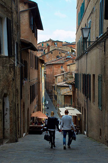 A photo of two people walking down a street