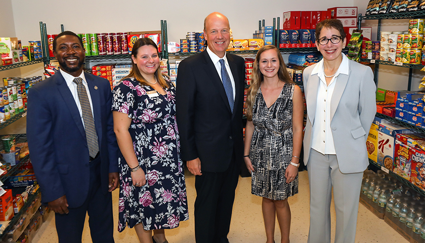 Group gathered in front of well-stocked food pantry shelves