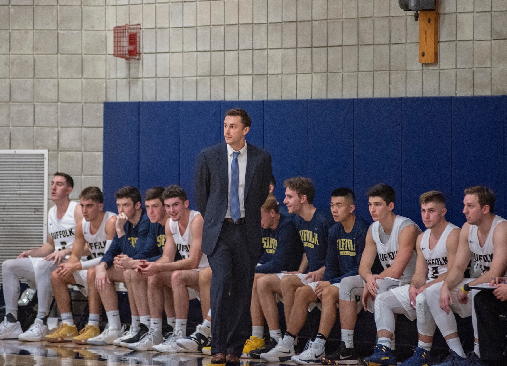 Image of a basketball coach with his players sitting on a bench.