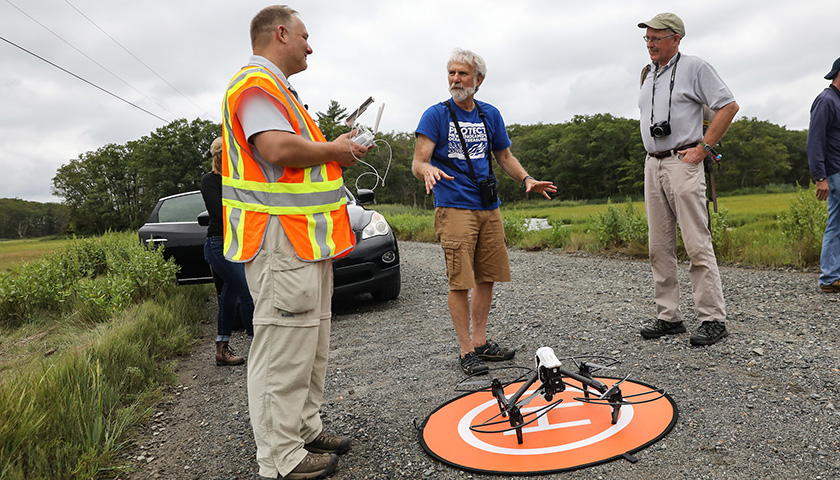 Drone is in foreground as three scientists talk