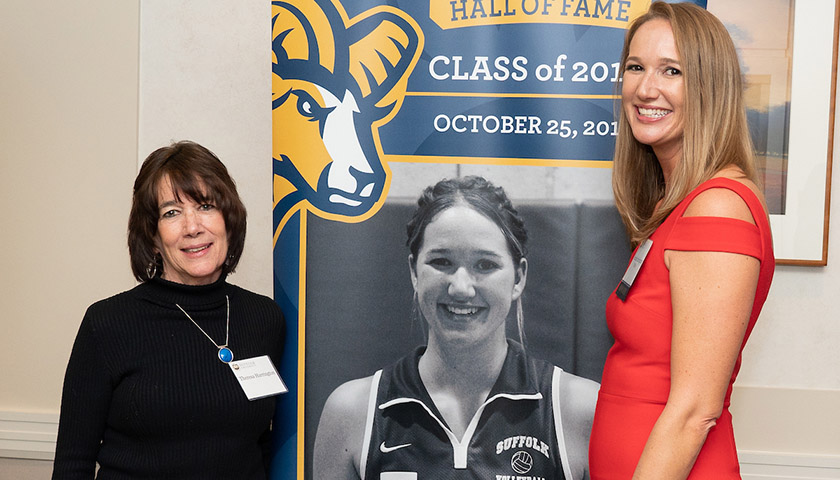 Harringtons in front of banner showing Theresa Harrington in Suffolk volleyball uniform