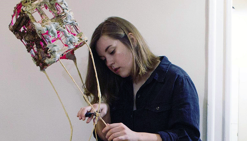 Woman doing detail work on a hanging sculptural piece