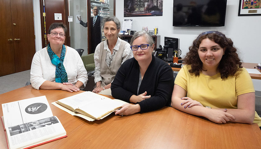 Four women with books open on table