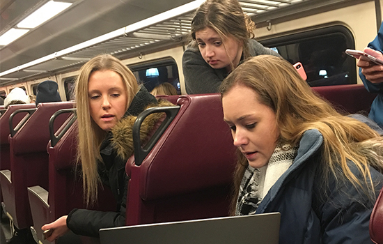 Students review their presentation on the commuter train