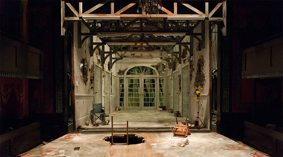 Dr. Faustus stage set is a derelict room with a hole in the floor and books strewn about