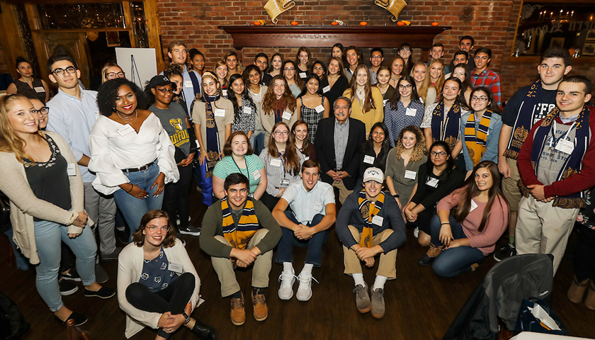 A smiling Leaonard Samia in the midst of a large group of students who have benefited from scholarships he funded