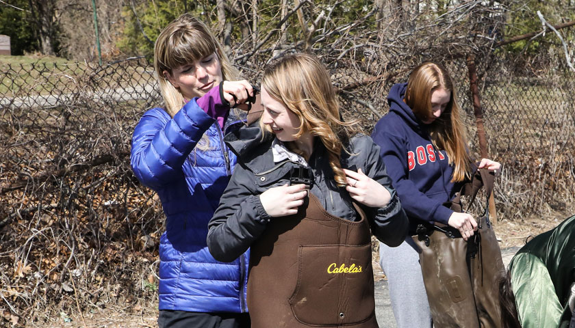 Professor Schiebel helps a student into waders at the fieldwork site