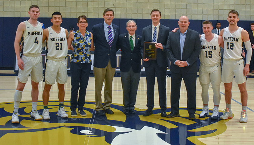 Jeff Juron holds plaque as group of officials and players pose at midcourt