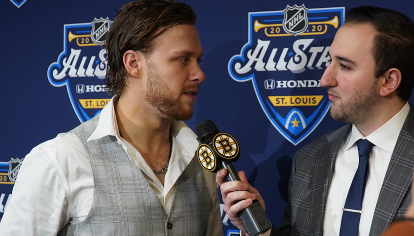 David Pastrnak. and Eric Russo, who holds microphone, with All Star logo in backdrop