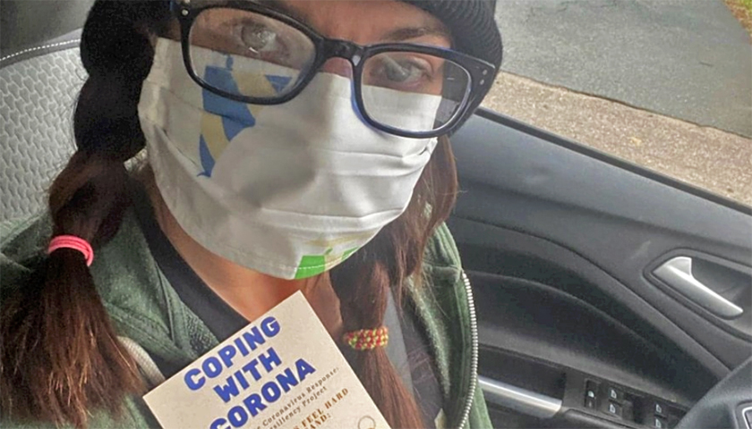 Lynne Shea wearing mask and holding information card about the coronavirus