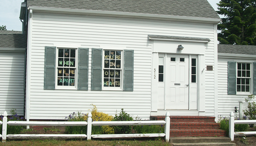 Old house with letters in windowpanes spelling out  When we're apart you're in our hearts