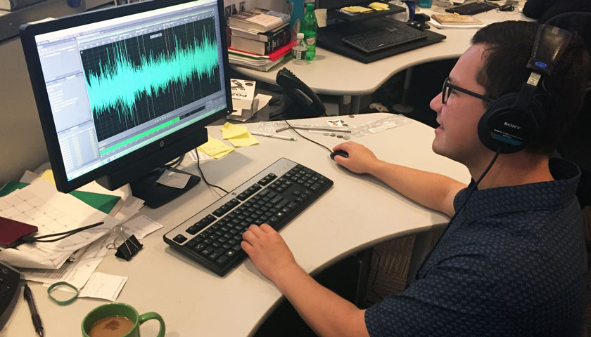 Diego Lopez wearing headphones at a desk editing audio files on a computer