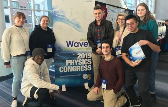 Students pose with poster at a physics research conference