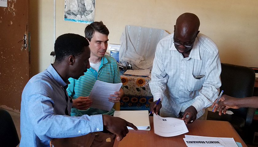 Moussa Cissé and Professor Peter Martelli confer with a doctor in a Guinean clinic