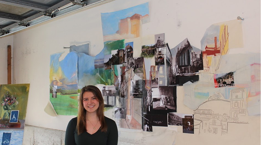 Student in garage studio with her collage on wall