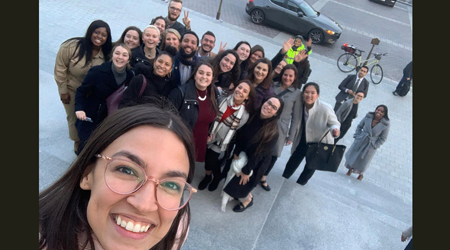 Congresswoman Alexandria Ocasio-Cortez in foreground as she takes selfie with Suffolk group