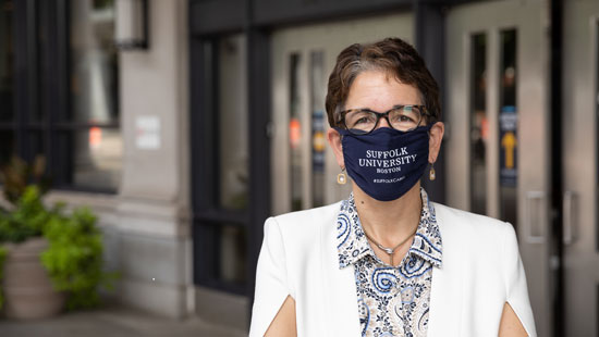 President Marisa Kelly wears a mask as she stands outdoors on Suffolk's campus