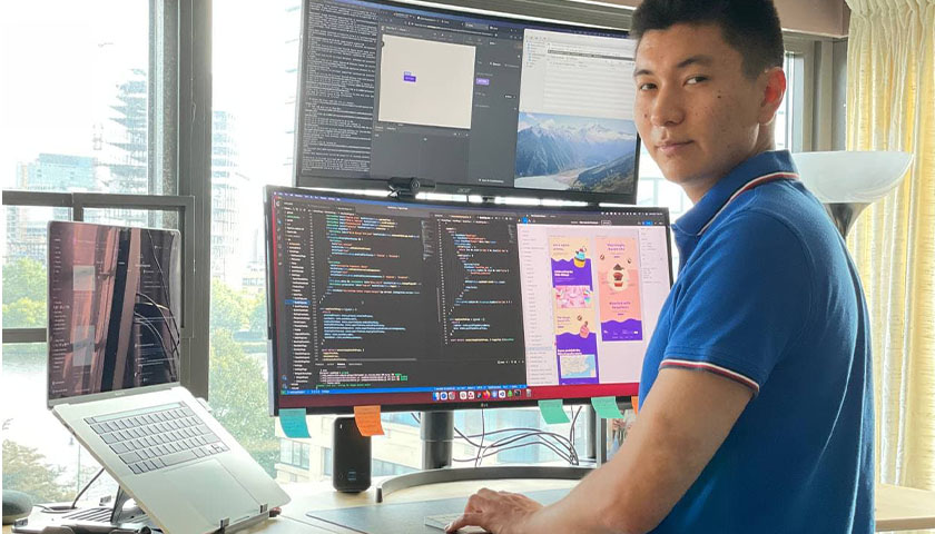 Math Champion Daniyar Aubekerov standing in front of a bank of computer screens