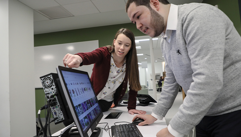 Two Suffolk University teaching assistants work at the computer.