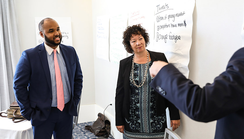 Two EMBA students discuss a presentation with a member of their cohort