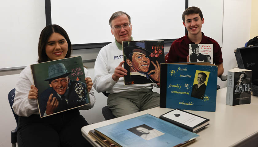 Elise Ferreira Aidar Coelho, Charlie St. Amand, and Michael Najarian hold Frank Sinatra record albums and books