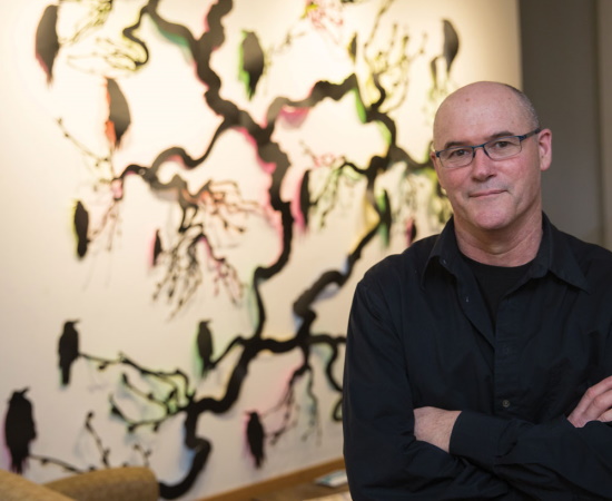 Randal Thurston stands in front of glass mock-ups of his work for the Lechmere T station