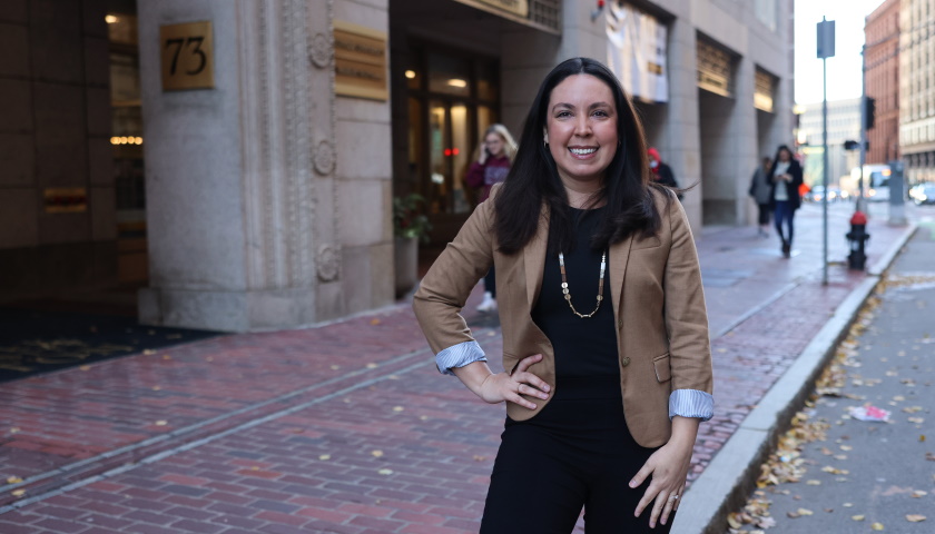 Lisa Rivera stands confidently in front of 73 Tremont Street on an early winter day with students passing in the background