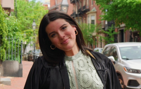 Sayler Tyson smiles as she wears her graduation gown on a Boston street