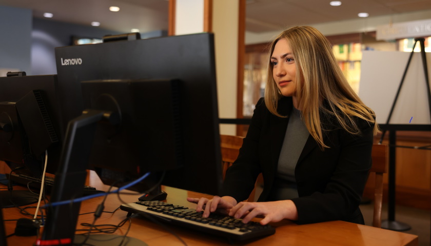 Mikaela types at a computer on Suffolk's campus