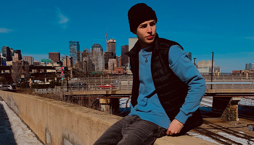 Fashion influencer Sean Grady poses while wearing Madewell clothing with the Boston skyline in the background