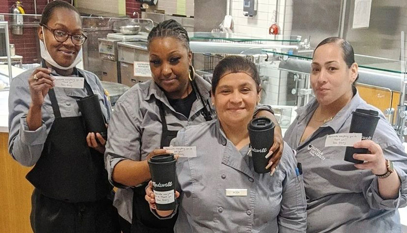 Café staff members Sharai Cooper, Lawshawna Small, Rose Cerritos, and Jessica Granados hold up Madewell mugs given to them by Sean Grady