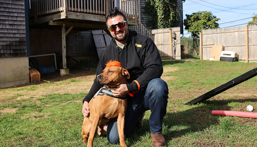 Veteran kneels with a canine friend from 22Mohawks