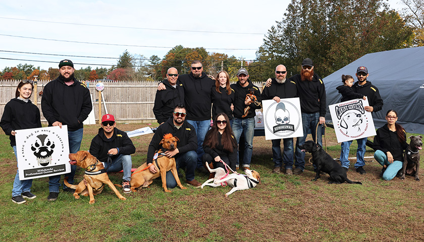 Pups for Vets veterans with posing with their canine friends in someone's yard