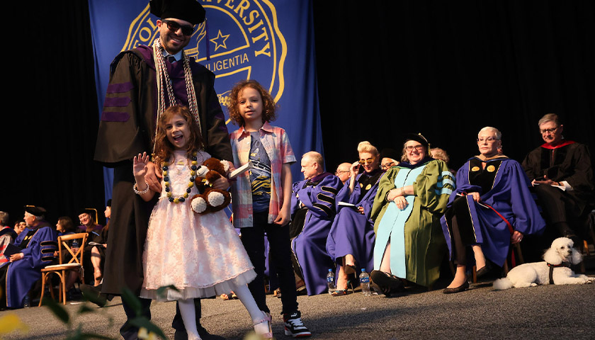 A Suffolk Law graduate sharing the big moment with his children on stage at the 2023 Suffolk Law School Commencement