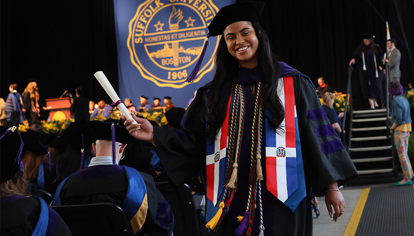 A student proudly shows off her diploma after leaving the stage at the 2023 Suffolk Law School Commencement
