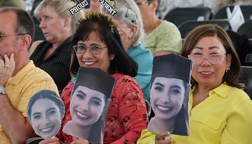 Proud parents with cutout faces of a daughter at the 2023 Law School Commencement