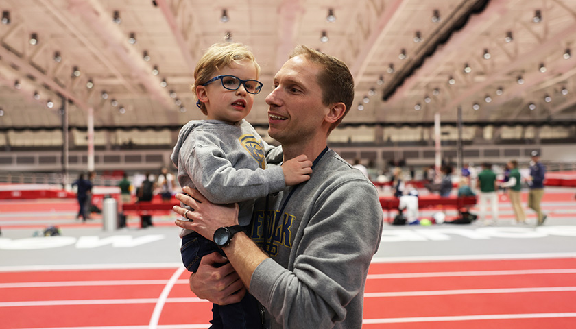 Head Coach Will Feldman holds son Landon at the New Balance Track