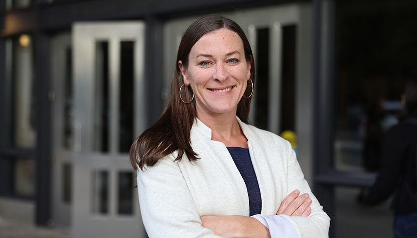 Professor Dyane O'Leary in white jacket in front of Law School