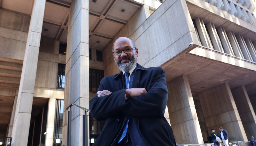 Charles Yancey stands with arms crossed in front of Boston City Hall