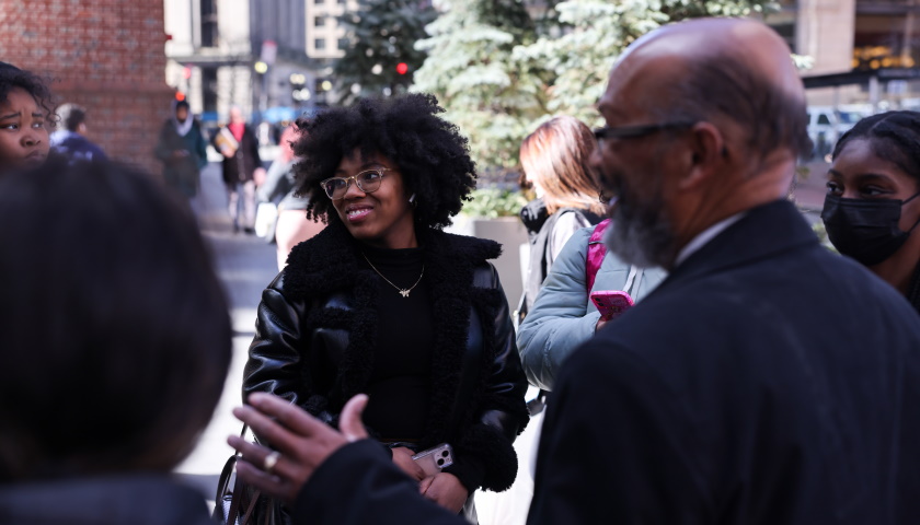 Sydney Weekes smiles as she speaks with classmates and Professor Charles Yancey outdoors in Boston