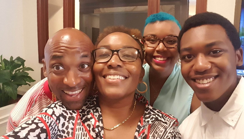 Image shows the Victorine family posing shoulder-to-shoulder and smiling, from left-to-right, father Raymond, mother Lander, Rae’Niqua, and her brother Raequan