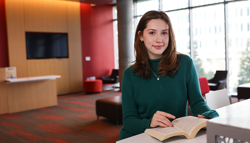 Meredith Melia sitting at a desk reading a book