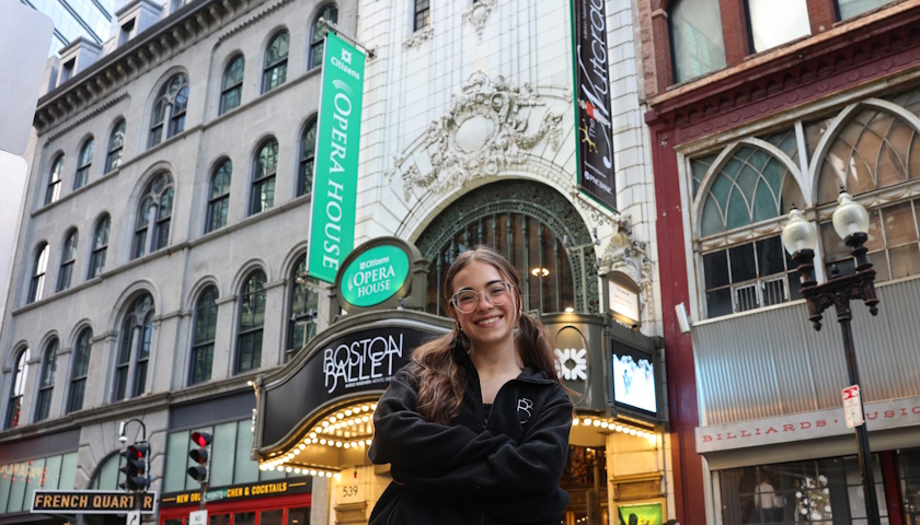 Paige D'Ambrosio smiles as she stands outside the Boston Opera House with signs for the Boston Ballet and The Nutcracker behind her