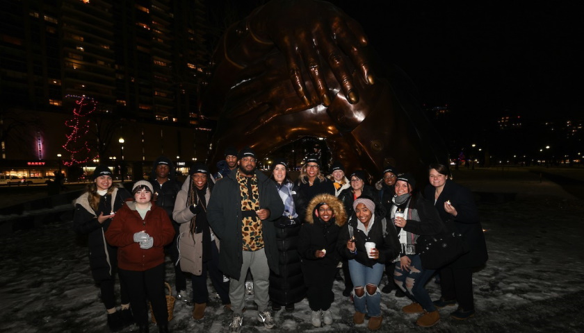 Members of the Suffolk community gathered at The Embrace sculpture on the Common at night