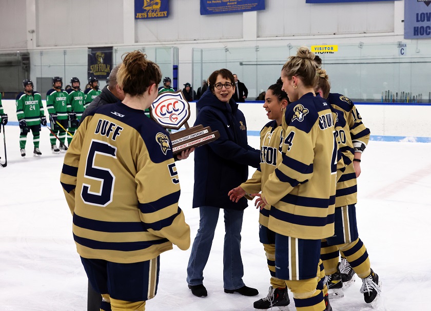 President Kelly celebrates at center ice  with the 2023 Commonwealth Coast Conference champion Suffolk women’s hockey team.