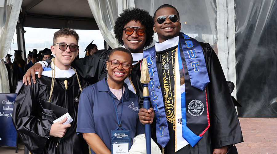 Three graduates and a friend smiling for the camera at the 2025 College of Arts & Sciences Commencement