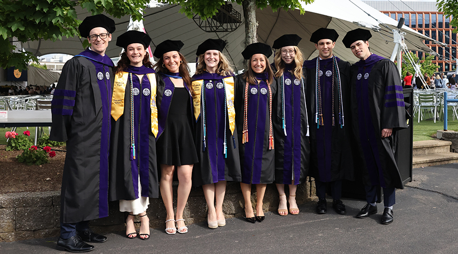 A group of Suffolk Law graduates standing in a line, wearing their tams and gowns